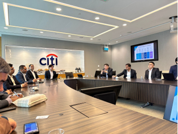 A group of professionals are engaged in a discussion during the Singapore Study Tour, seated around an oval-shaped table in a meeting room at Citibank Singapore Limited.